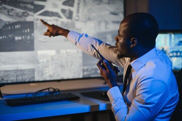 Serious African American security guard watching cctv video in surveillance room