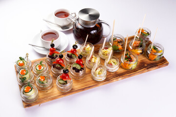 Various snacks on a tray, tea on a white background.