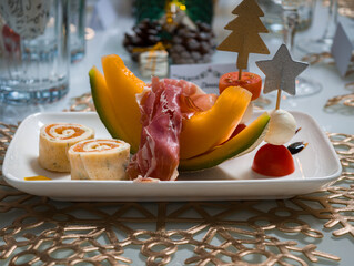 Festive appetizer plate with melon, prosciutto, and tomato skewers for holiday celebrations