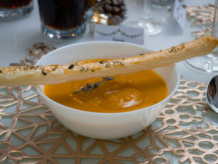 Pumpkin soup with breadstick on a festive table setting, perfect for autumn and winter holidays