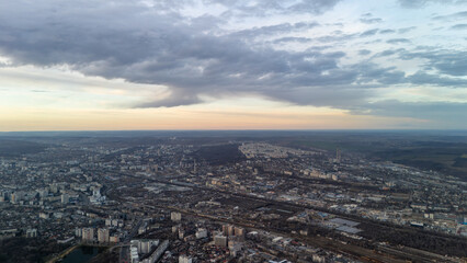 Aerial view of a cityscape with dramatic clouds and sunset horizon