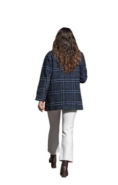 femme vue de dos marchant en automne, portant un manteau &agrave; carreaux bleu marine, pantalon clair &eacute;vas&eacute; et bottines &agrave; talons, elle semble regarder son smartphone
