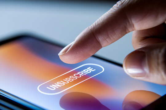 Close up of person's finger hovering over unsubscribe button on mobile phone screen