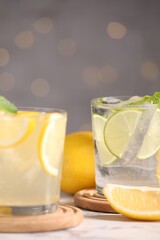 Tasty citrus cocktails in glasses on white table against blurred lights, closeup
