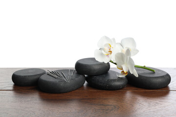 Acupuncture needles, orchid flowers and spa stones on wooden table against white background