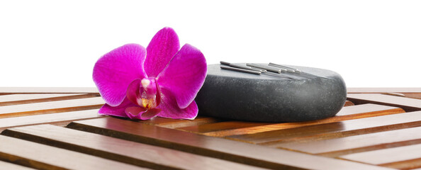 Acupuncture needles, orchid flower and spa stone on wooden table against white background