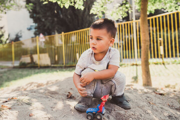 Toddler playing with toy truck in sandbox at kindergarten