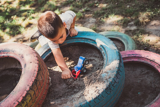 Child playing with toy car in tire sandbox at playground