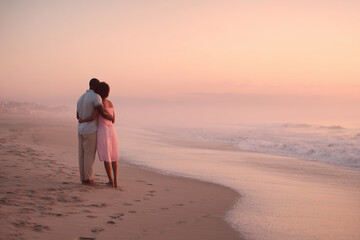 Romantic couple embracing on a serene beach at sunset with soft pastel skies and gentle waves