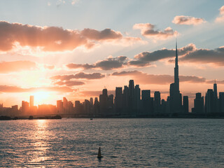 Dubai skyline at golden hour with dramatic sunset sky and calm water waves, dubai Creek Harbour...