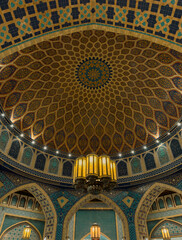 Naklejka premium Opulent chandelier on patterned Islamic dome ceiling with arabesque geometric design