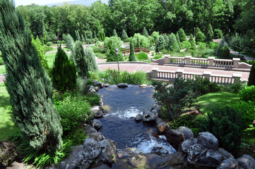 historical park with a walking path, thuja fir trees, antique sculptures, pine needles, a pond, a...