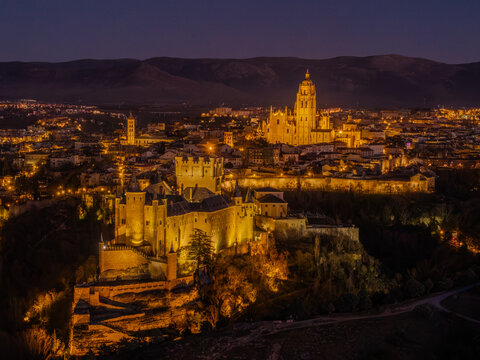 Aerial view of the Alc&Atilde;&iexcl;zar of Segovia and Segovia Cathedral bathed in golden light against the dark sky, Segovia, Castilla y Le&Atilde;&sup3;n, Spain.