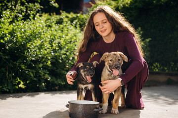 Near a water or food dish. Woman is with cute dogs outdoors
