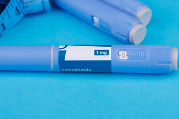 Blue table with semaglutide pens, white pill bottle and scattered tablets for modern healthcare and...