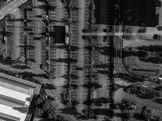Black and white aerial photograph of a parking lot with distinctive shadow patterns and roads,...