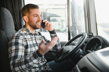 Young professional driver communicating over mobile phone while driving a truck