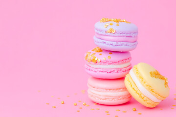 Delicate pastel macarons with gold sprinkles on soft pink background elegant dessert presentation