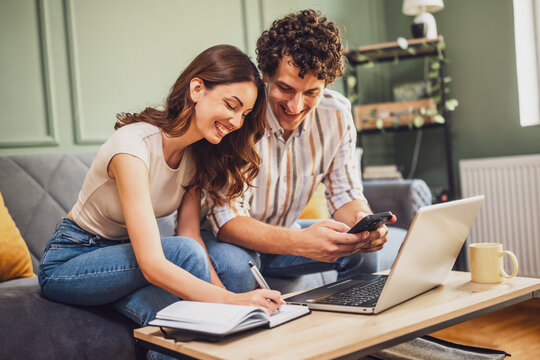 Couple discussing home finance on laptop and calculating family budget in living room.