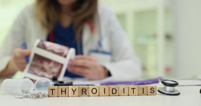 Wooden blocks show Thyroiditis put near stethoscope and scattered pills. Light enters room creating calm while lady doctor studies disease treatment