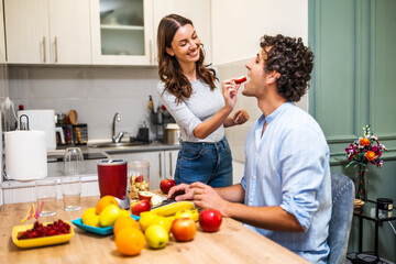 Adult couple is preparing smoothie in their kitchen. They have various fruits ready to be mixed in electric juicer.