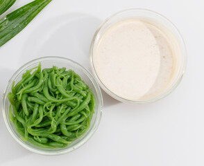 Traditional Thai dessert lod chong pandan noodles served with sweet coconut milk in glass bowls, a refreshing Southeast Asian treat.
