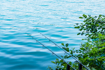 two fishing rods under calm turquoise lake. calm water surface. crystal clear turquoise water....