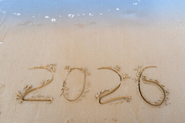 2026 numbers written in the sandy beach. Sea wave background