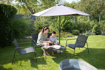 Woman and a kid cooking and eating inthe backyard