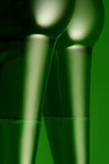 Two green beer bottles arranged to resemble elegant female legs with playful mood. Concept of...