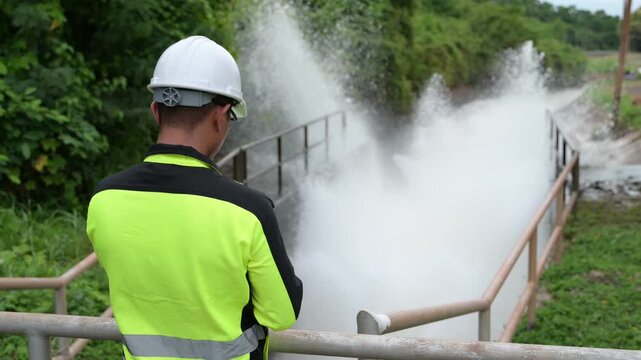 Engineer working at hydroelectric dam inspecting water release, checking gates, analyzing daily flow, monitoring water quality, ensuring maintenance, safety, sustainable energy, and environmental mana