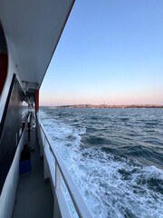 Scenic view from the deck of a traditional Istanbul vapur, showing the Asian side of the city and the sparkling waters of the Bosphorus. 