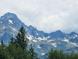 La Thuile, Val D'Aosta, July 02 2025: Panoramic view to the alps, beautiful green landscape reflected in a small natural lake. Beautiful blue sky with some clouds. Mountains with a little snow. Aerial