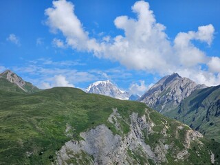 La Thuile, Val D'Aosta, July 02 2025: Panoramic view to the alps, beautiful green landscape reflected in a small natural lake. Beautiful blue sky with some clouds. Mountains with a little snow. Aerial