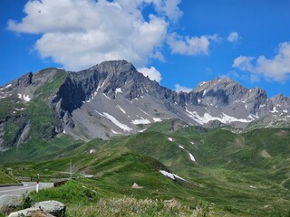 La Thuile, Val D'Aosta, July 02 2025: Panoramic view to the alps, beautiful green landscape reflected in a small natural lake. Beautiful blue sky with some clouds. Mountains with a little snow. Aerial