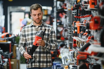 A man in a hardware store choosing a tool