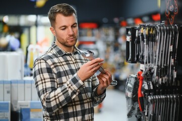 A male buyer chooses a toolbox in a hardware store. A large selection of tools.