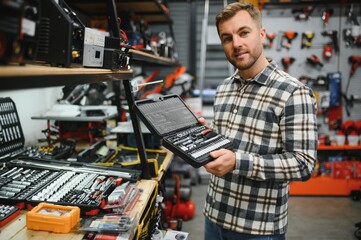 A man in a hardware store choosing a tool