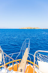 Front deck of yacht sailing in blue sea with islands on the horizon