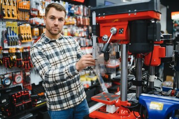 A male buyer chooses power tools in a hardware store. A large selection of tools