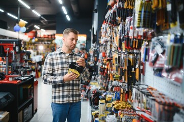 A male buyer in a modern hardware store. A large selection of tools and various household and...