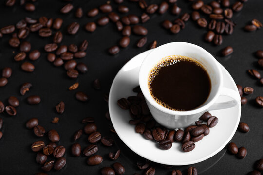 A espresso cup filled with dark coffee surrounded by roasted beans on reflective surface. - Powered by Adobe