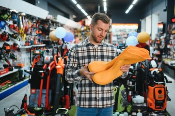 Man chooses rubber boots at a garden supply store