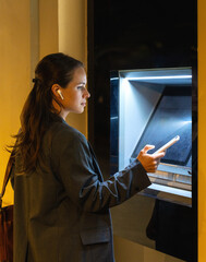 Urban woman using smartphone at ATM for cardless mobile banking transaction