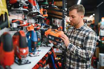 A man in a hardware store choosing a tool