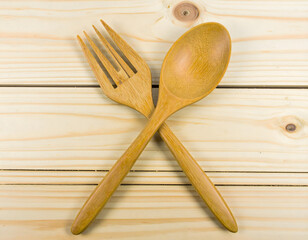 Wooden Spoon and Fork Crossed on a Light Wooden Surface, Top-Down Perspective for Culinary Concepts