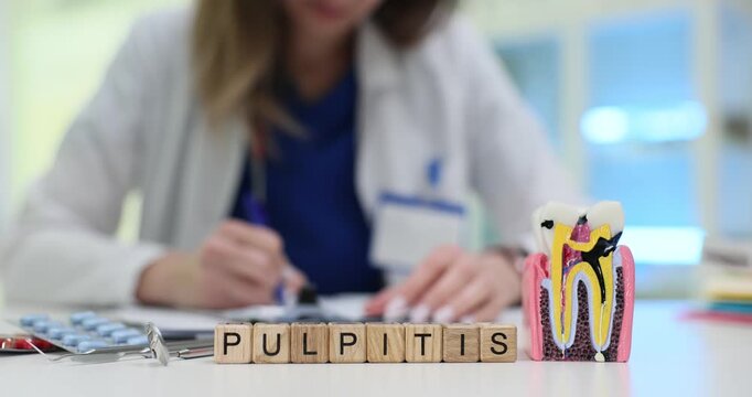 Word Pulpitis appears on cubes in front of model tooth and writing doctor. Dental model and medical pills imply oral disease study or diagnosis