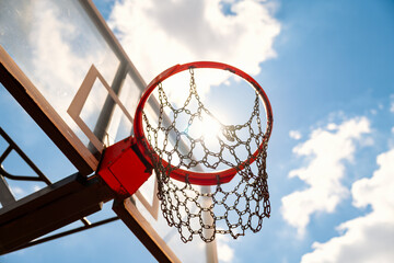 Low angle view of basketball hoop against blue sky with sunlight