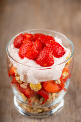 Greek yogurt, granola and strawberry on the rustic background. Selective focus.