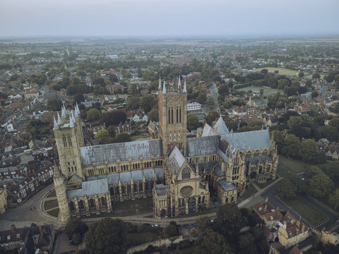 Aerial view of the magnificent Lincoln Cathedral stands tall amidst a sea of green, its gothic architecture a testament to time, Lincoln, England, United Kingdom.